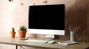 Aesthetic Home Office Ideas: The Complete 2026 Style Guide for a Beautiful, Productive Workspace 11 Close-up of an aesthetic desk setup with a monitor on a wood riser, a small pothos plant, a ceramic tray with daily items, a brass desk lamp, and clean cable management