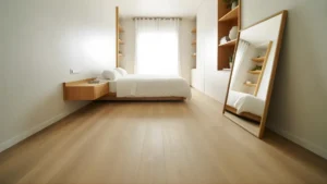 Small bedroom with light walls, a wall-mounted nightstand, a large floor mirror, and vertical shelving to maximize space. 