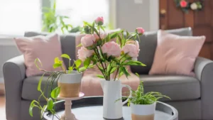 A bright spring living room with sage green and blush cushions, a linen throw, tulips in a glass vase, and natural light streaming through sheer curtains.