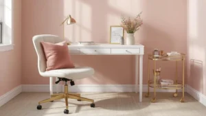 A blush and gold home office showing a white desk with gold legs, an ergonomic chair with a blush cushion, and a gold bar cart used for storage.