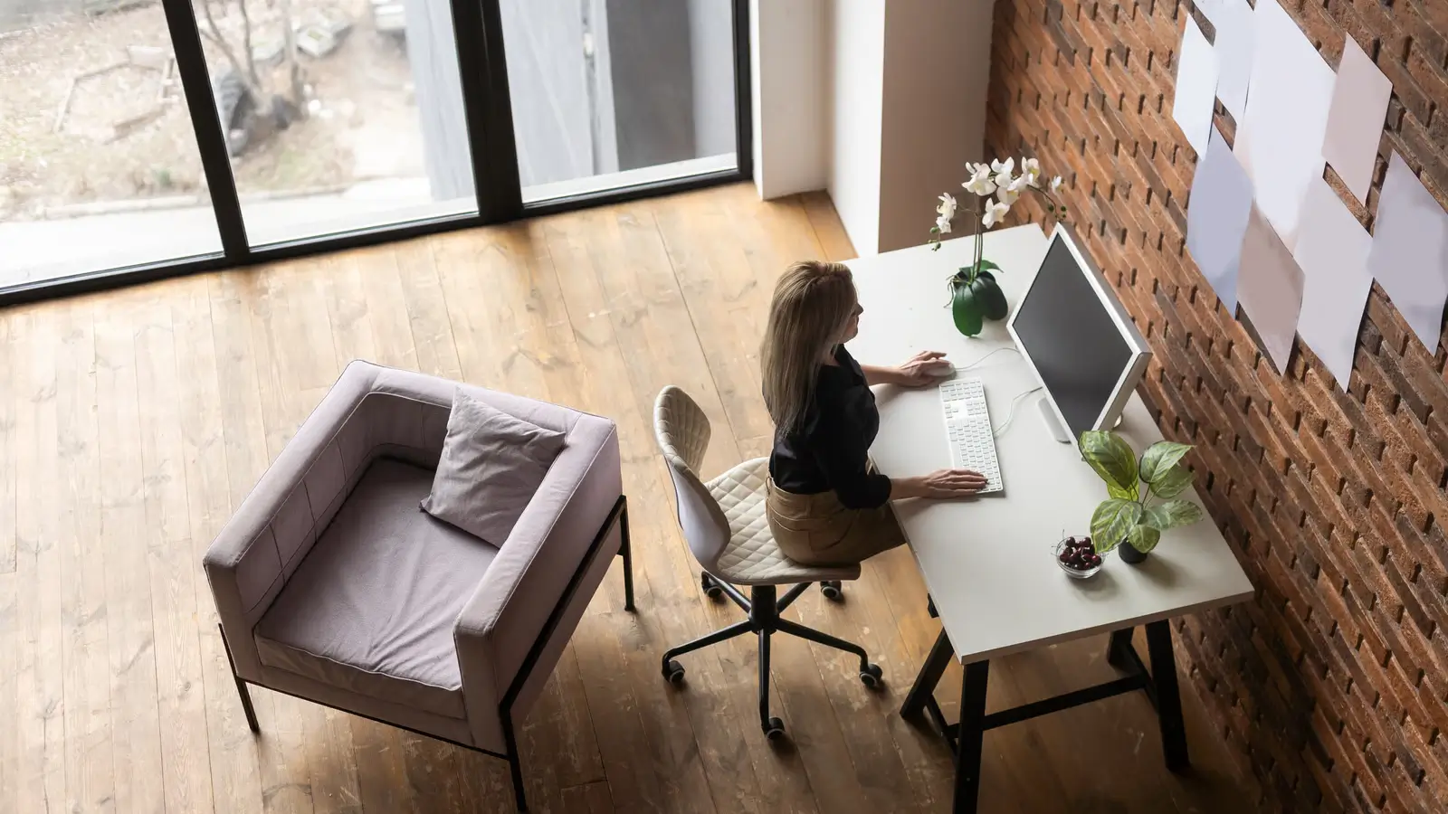 Ergonomic Chair Petite Women - A petite woman adjusting an ergonomic office chair in a bright home office with a desk, laptop, and soft neutral decor.
